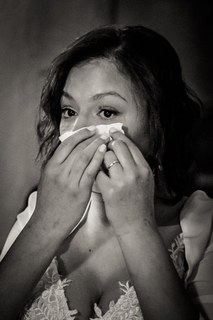 Sarah im Hochzeitskleid, von Emotionen überwältigt und in Tränen aufgelöst. Die Szene fängt einen Moment tiefer Verletzlichkeit und Freude zugleich ein, passend zur Reise zwischen Blüten und Narben, die den Weg der Selbstheilung begleitet.